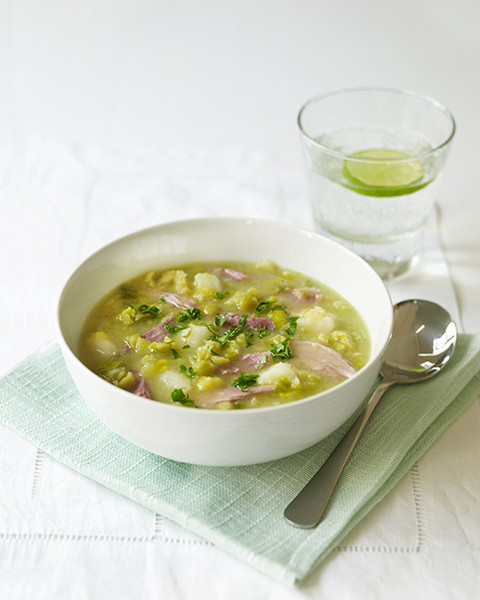Bowl of pea and ham soup, spoon, and a glass of water