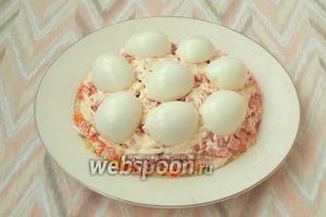 Половинки яиц выложить сверху колбасы белком вверх, образовывая холмики.