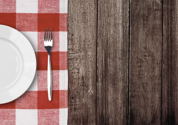 Белая тарелка и вилка на старый деревянный стол с красного флажка tablec Стоковое Изображение