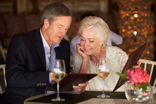 Пожилые супружеские пары, выбирая из меню в ресторане Стоковое Фото