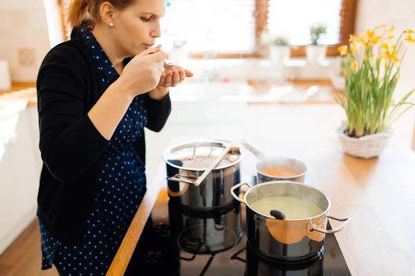 Домохозяйка, дегустации пищи в кухне — стоковое фото