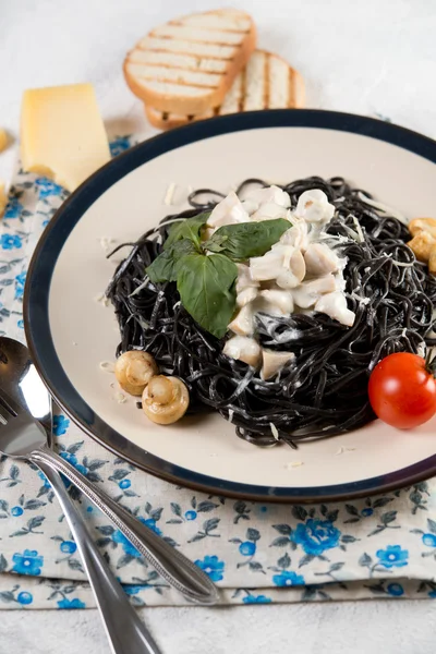 Традиционное итальянское блюдо. Спагетти с чернилами каракатицы и сливочным соусом с грибами Стоковое Изображение