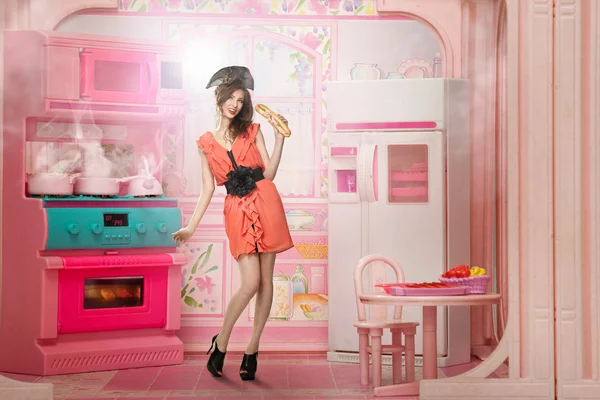 Молодая женщина, как куклу cokking розовый кухне — стоковое фото