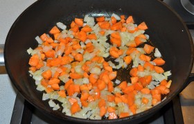 На хорошо разогретую толстостенную сковороду с растительным маслом выкладываем лук, и на огне около среднего пассеруем (обжариваем) его, помешивая, минут 5-7. Добавляем морковь и немного огня, жарим еще 3-5 минут.