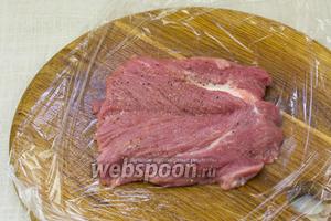 Мясо посолить и поперчить по вкусу. Накрыть плотным полиэтиленом, чтобы не летели брызги. 