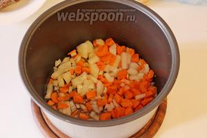 В чашу мультиварки налить масло, выложить лук и морковь. Установить режим «Выпечка»/«Жарка» на 20 минут и готовить 5 минут.
