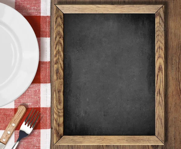 Вид сверху доски меню на столе с пластиной, ножом и вилкой — стоковое фото