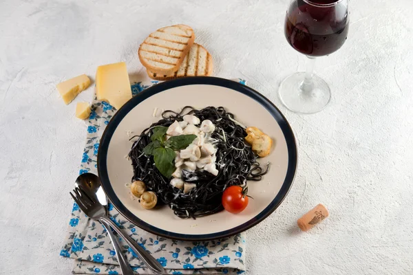 Традиционное итальянское блюдо. Спагетти с чернилами каракатицы и сливочным соусом с грибами Стоковое Фото